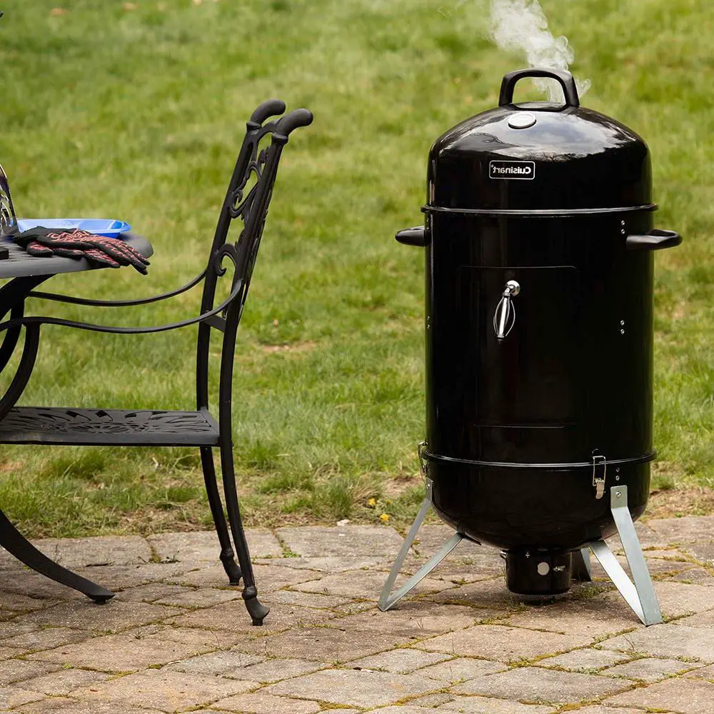 A charcoal smoker in the yard.