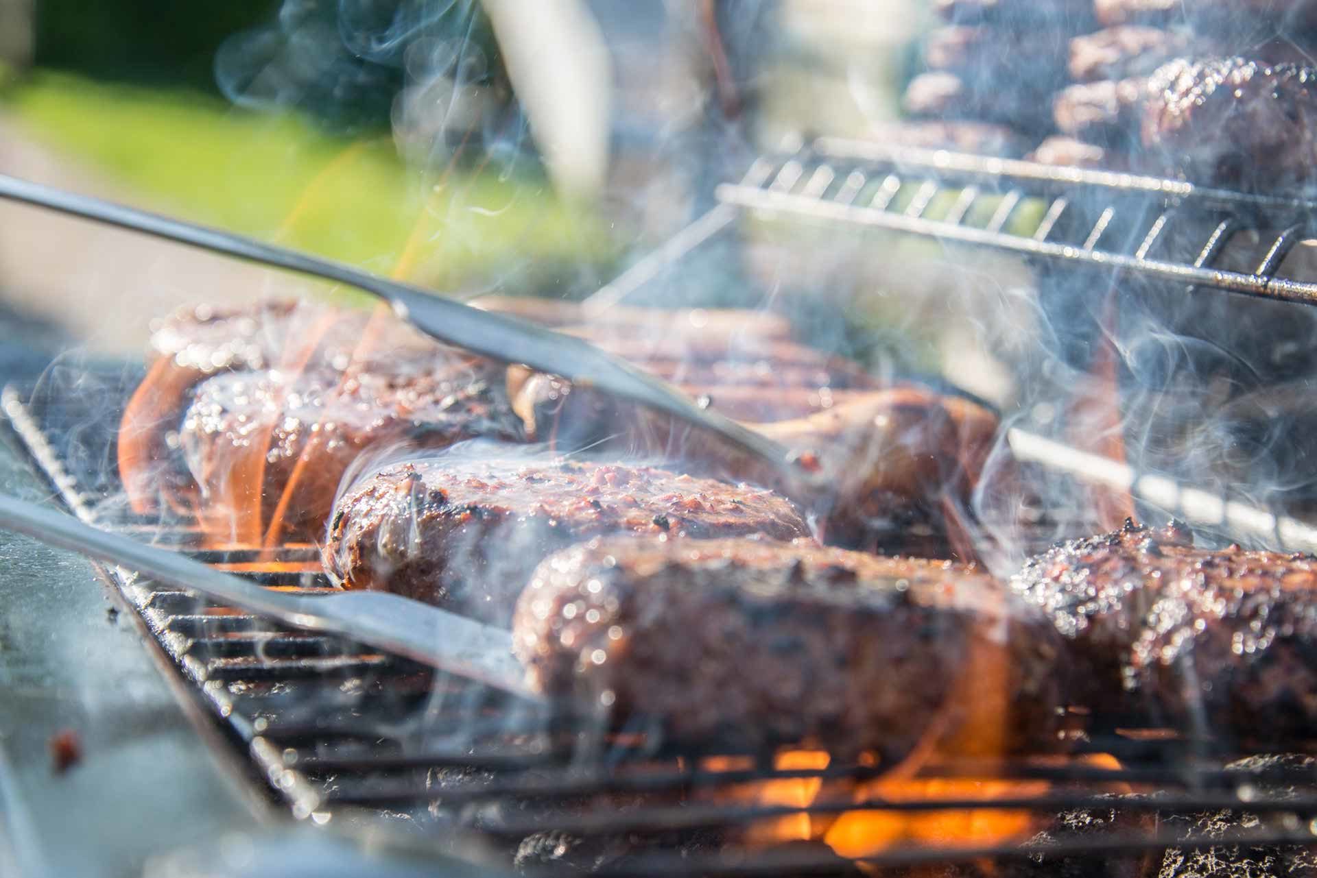 what-are-the-best-charcoal-grill Family man cooking hamburgers.