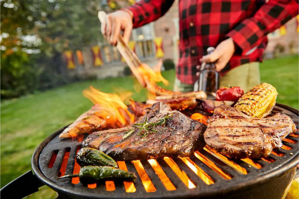 Man holding a beer grilling meat on a BBQ