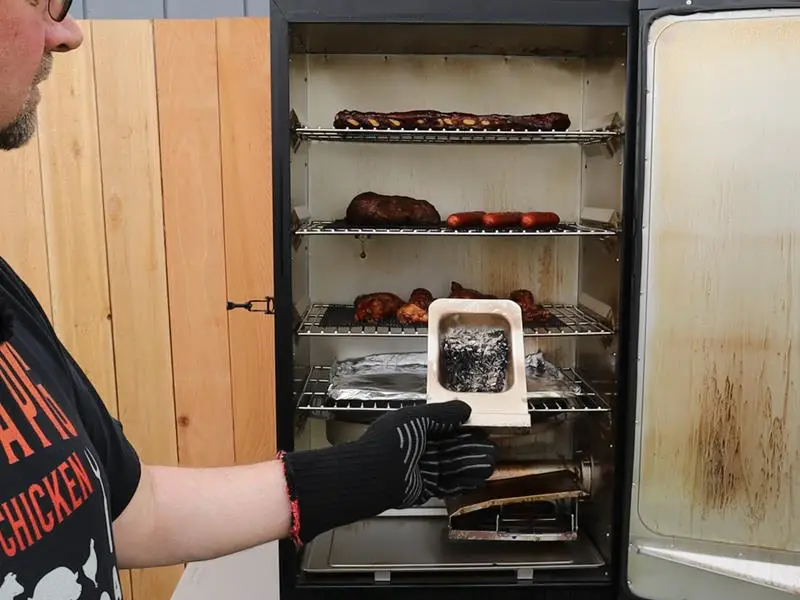 examining the wood chip pan inside a Masterbuilt electric smoker 140B
