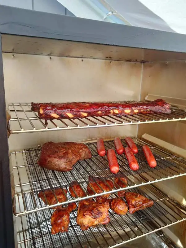 The inside of a Masterbuilt Electric Smoker with food items being smoked inside.