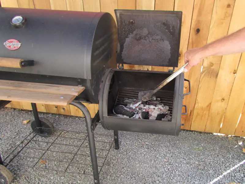 Robert author of pioneersmokehouses manages a small fire in a Chargriller smokin Pro offset smoker
