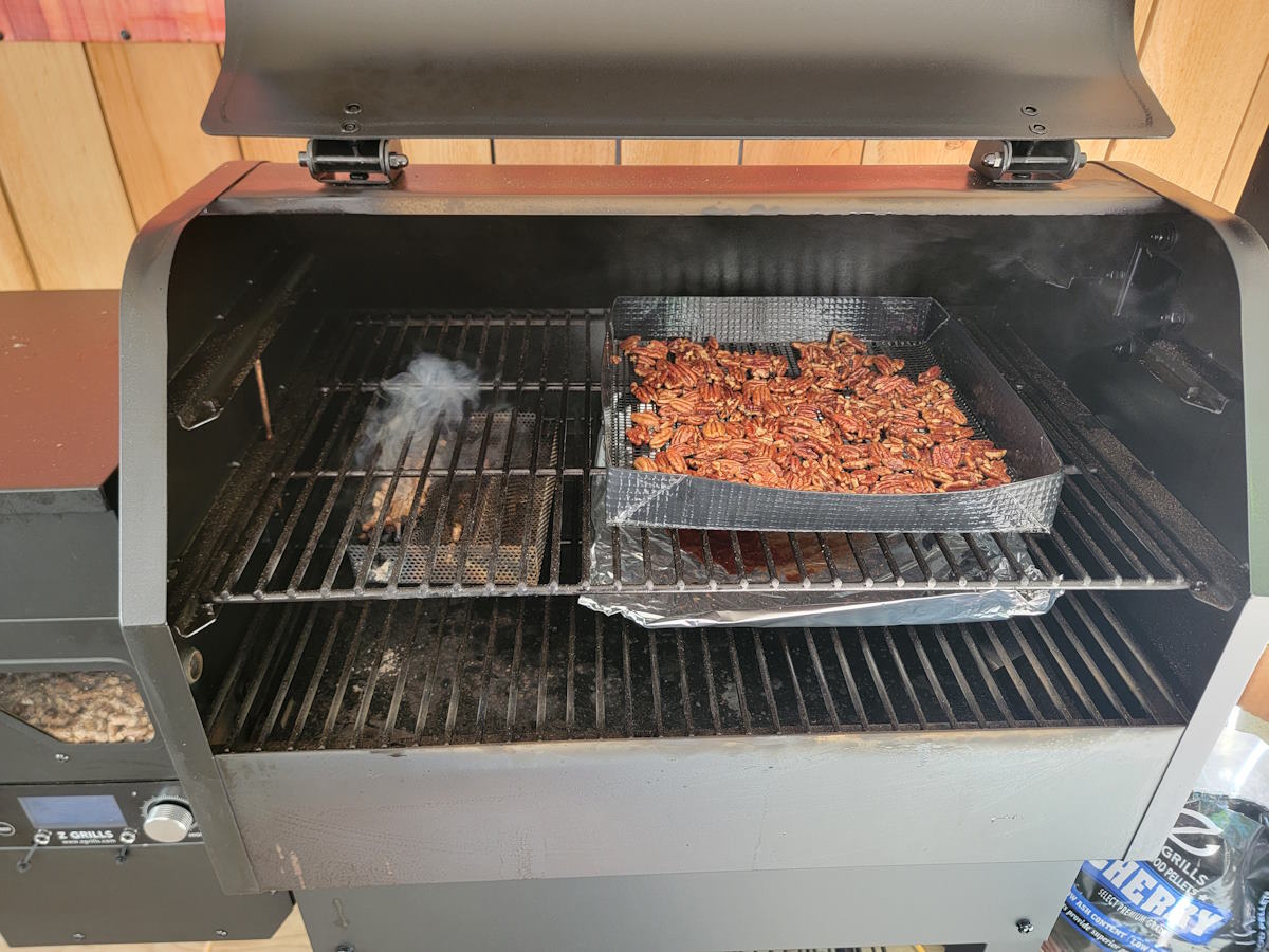 How to make smoked candied pecans in a Z Grill pellet smoker Smoked candied pecans cooking in a Z Grill pellet smoker with visible smoke and grill basket